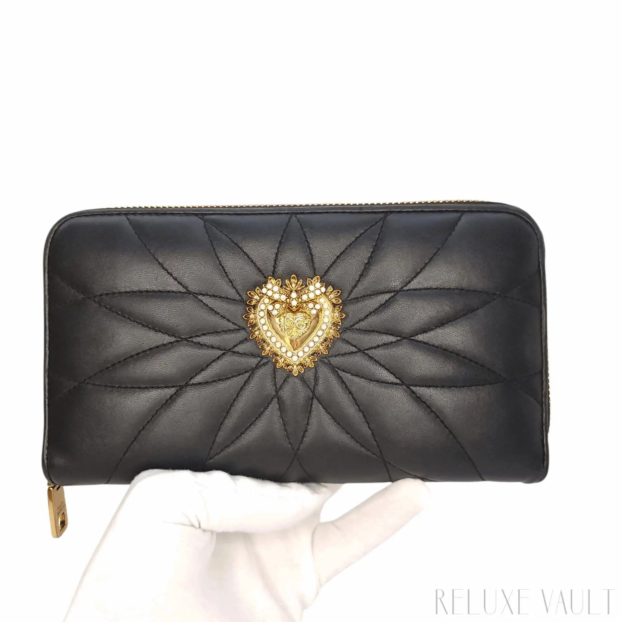 Black quilted leather wallet featuring a gold-toned heart emblem adorned with pearls and intricate detailing.